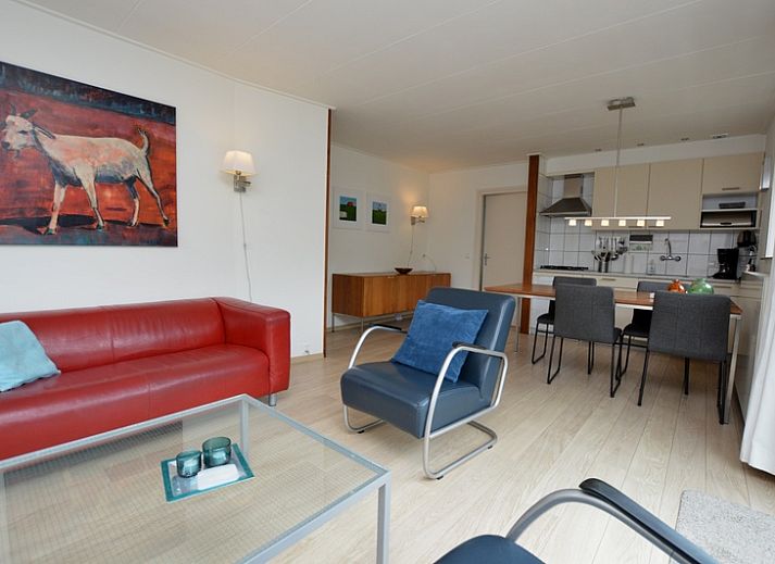 Helles Wohnzimmer des Ferienhauses de Parel 192 in De Dennen, Texel mit bequemen Sitzgelegenheiten und Blick auf den Garten.