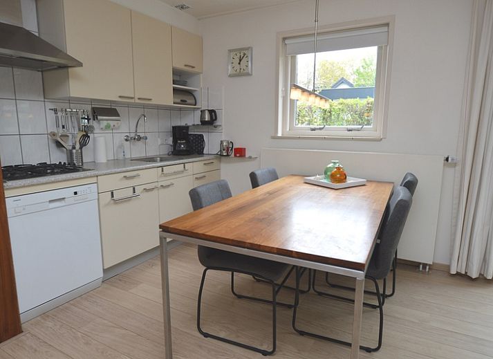 Helles Wohnzimmer des Ferienhauses de Parel 192 in De Dennen, Texel mit bequemen Sitzgelegenheiten und Blick auf den Garten.