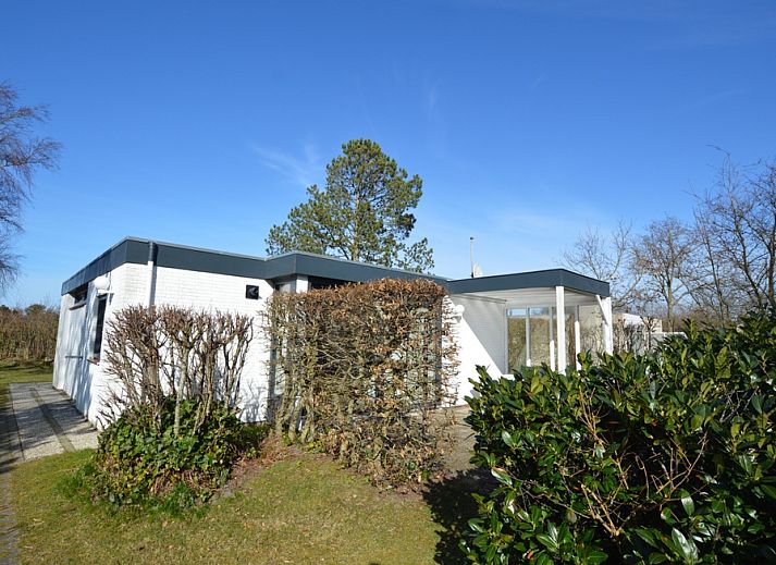 Das Ferienhaus de Parel 198 in De Dennen, Texel, bietet eine ruhige Aussicht auf die gruene Umgebung und den blauen Himmel.