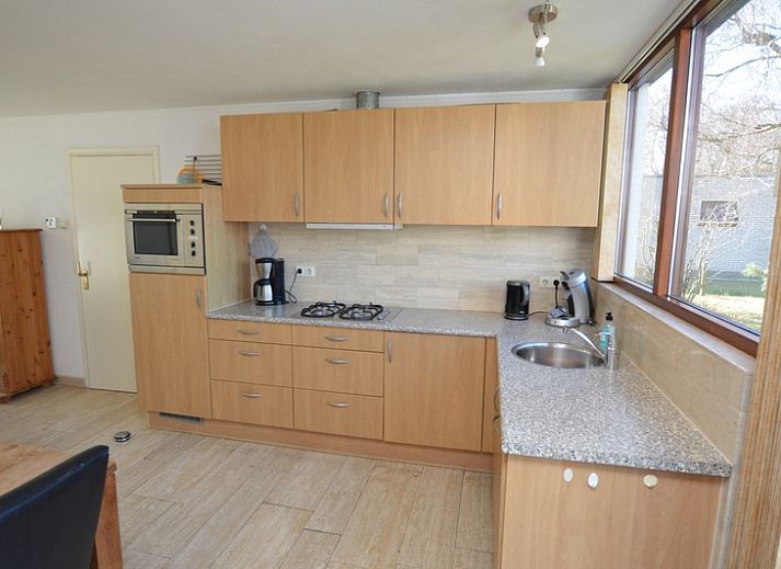 Gemuetliches Wohnzimmer des Ferienhauses de Parel 198 in De Dennen, Texel, mit bequemen gruenen Sofas und viel Tageslicht.