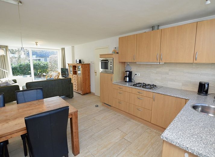 Gemuetliches Wohnzimmer des Ferienhauses de Parel 198 in De Dennen, Texel, mit bequemen gruenen Sofas und viel Tageslicht.