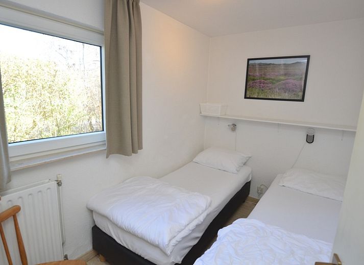 Gemuetliches Wohnzimmer des Ferienhauses de Parel 198 in De Dennen, Texel, mit bequemen gruenen Sofas und viel Tageslicht.