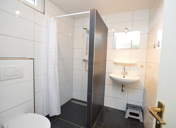 Gemuetliches Wohnzimmer des Ferienhauses de Parel 198 in De Dennen, Texel, mit bequemen gruenen Sofas und viel Tageslicht.