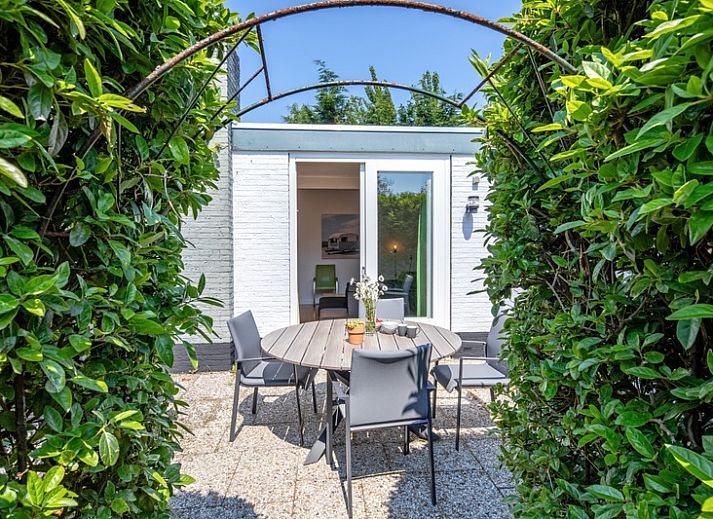 Gezellig terras bij Bungalowpark 't Luwe Land - 7B - De Wijnhof, De Dennen, Texel, omgeven door groene heggen.