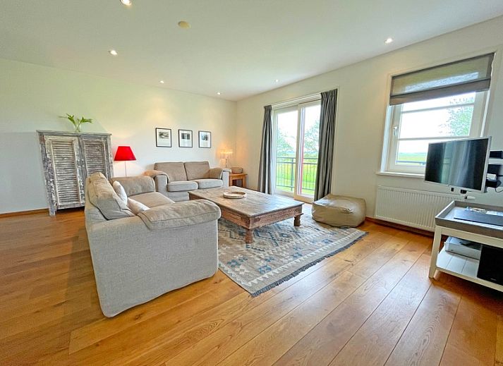 Gemuetliches Wohnzimmer im Appartement Bos en Duin 40, De Dennen, Texel mit bequemer Sitzecke und Blick auf die Natur.