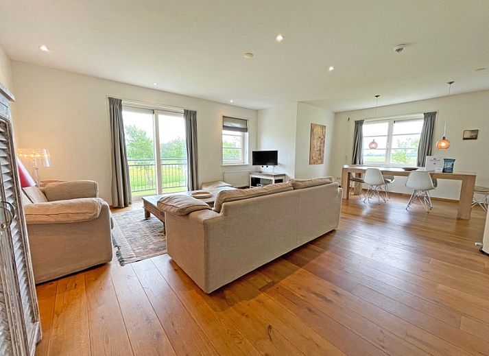 Gemuetliches Wohnzimmer im Appartement Bos en Duin 40, De Dennen, Texel mit bequemer Sitzecke und Blick auf die Natur.