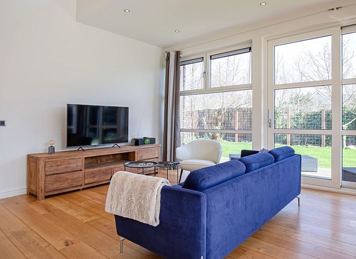 Side view of Holiday Home De Vlinder in De Dennen, Texel, with sunny terrace and green garden.
