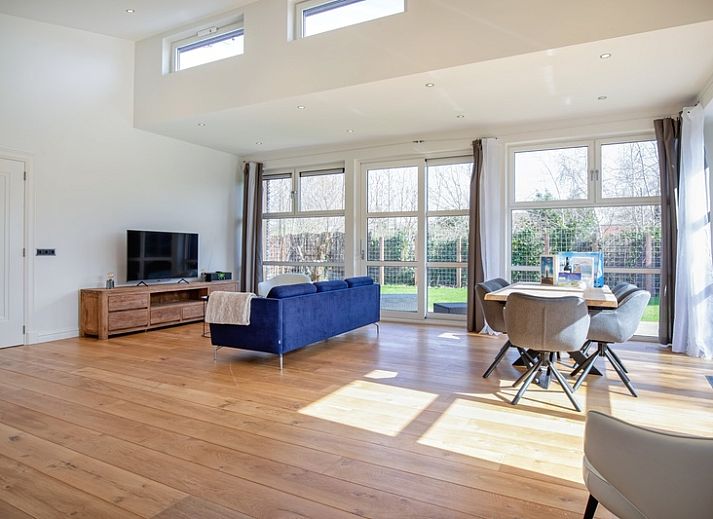 Side view of Holiday Home De Vlinder in De Dennen, Texel, with sunny terrace and green garden.