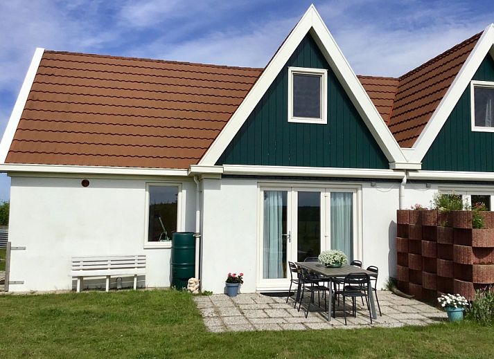 Aussenansicht von Haus 6, einem charmanten Ferienhaus in De Dennen, Texel, mit sonniger Terrasse und gruener Umgebung.