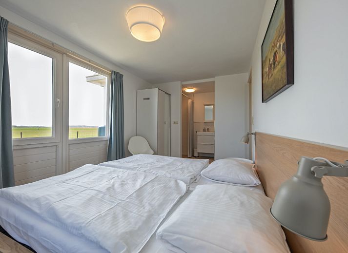 Aussenansicht von Haus 6, einem charmanten Ferienhaus in De Dennen, Texel, mit sonniger Terrasse und gruener Umgebung.