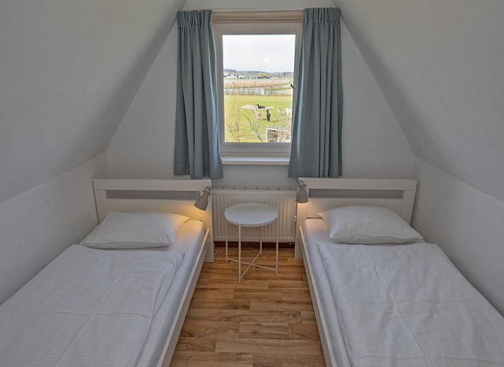 Gemuetliches Wohnzimmer von Cottage 6 in De Dennen, Texel, mit bequemer Sitzecke und Gartenblick.