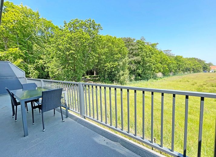 Offenes Wohnzimmer und Kueche im Appartement Bos en Duin 31, De Dennen, Texel mit stilvollen Moebeln und buntem Teppich.