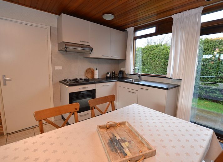 Gemuetliches Wohnzimmer im Holiday home de Parel 258, De Dennen, Texel, mit bequemen Sofas und Blick auf den Garten.