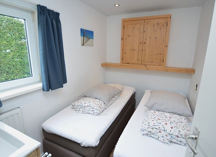 Gemuetliches Wohnzimmer im Holiday home de Parel 258, De Dennen, Texel, mit bequemen Sofas und Blick auf den Garten.