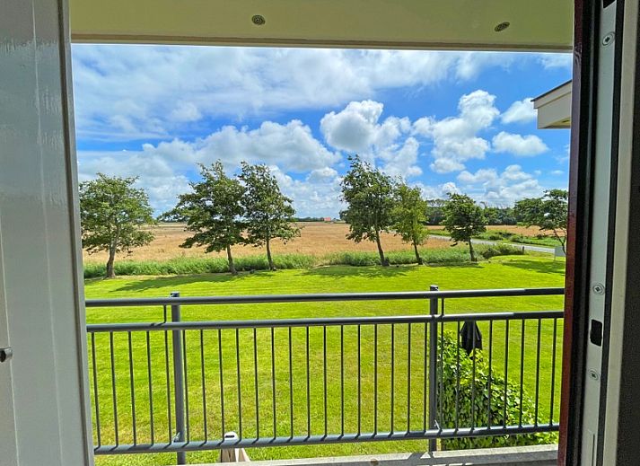 Uitzicht vanuit de woonkamer van Appartement Bos en Duin 41 in De Dennen, Texel met een serene landelijke omgeving.