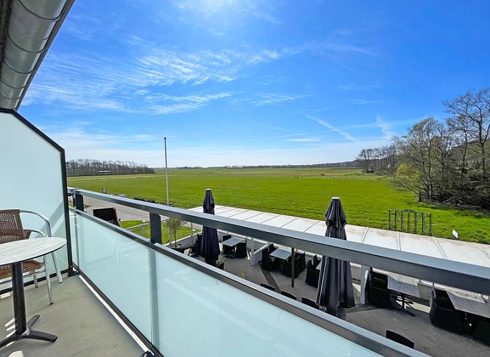 Lichte en ruime zitkamer van Appartement Bos en Duin 18, De Dennen, Texel met comfortabele meubels en uitzicht op de natuur.