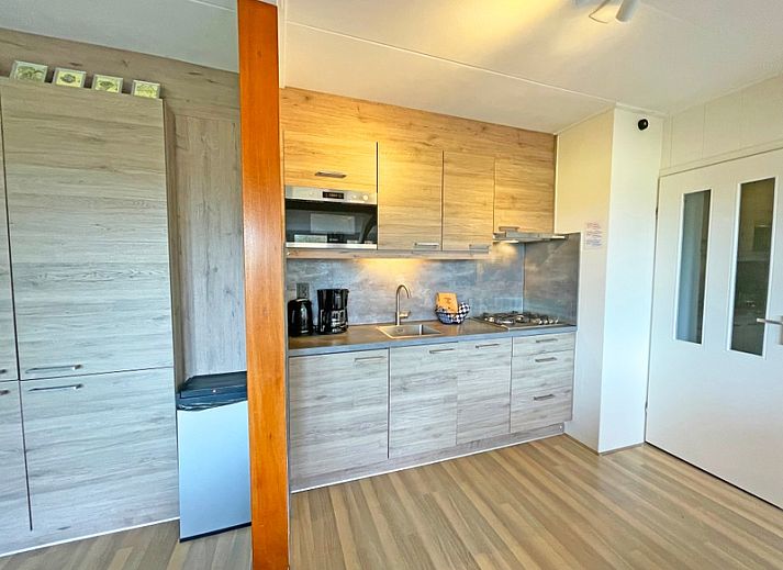 Gezellige eetruimte in Appartement Bos en Duin 36, De Dennen, Texel met houten tafel en rode stoelen.