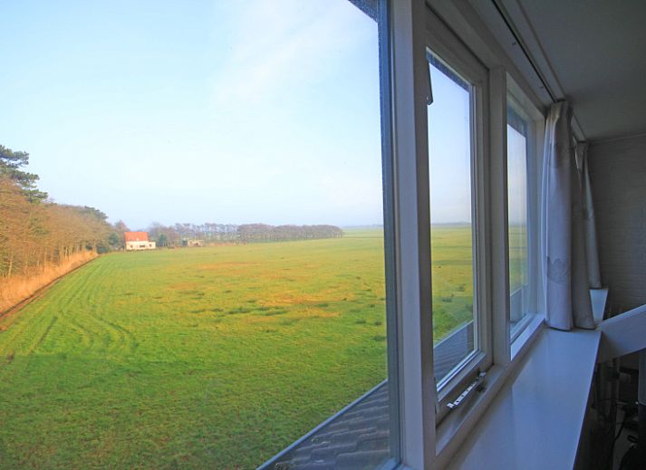 Gezellige eetruimte in Appartement Bos en Duin 36, De Dennen, Texel met houten tafel en rode stoelen.