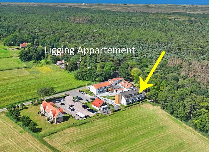 Gezellige eetruimte in Appartement Bos en Duin 36, De Dennen, Texel met houten tafel en rode stoelen.