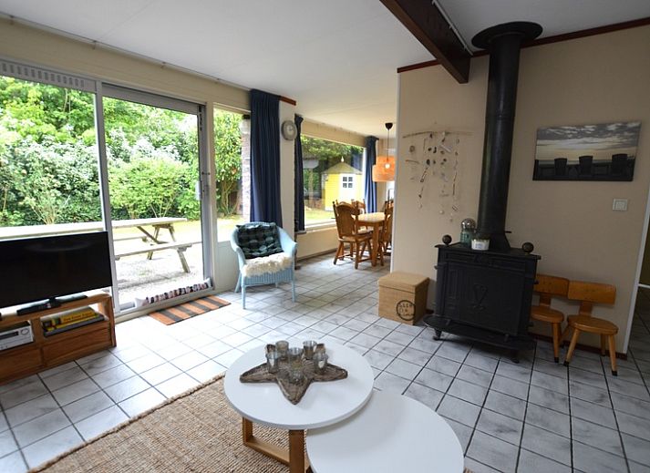 Gezellige woonkamer in Bungalow Verste Coogh 56, De Dennen, Texel, met comfortabele banken en uitzicht op de natuur.