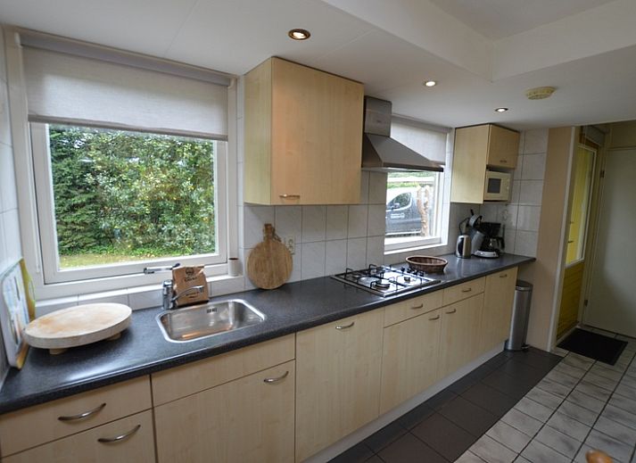 Gezellige woonkamer in Bungalow Verste Coogh 56, De Dennen, Texel, met comfortabele banken en uitzicht op de natuur.