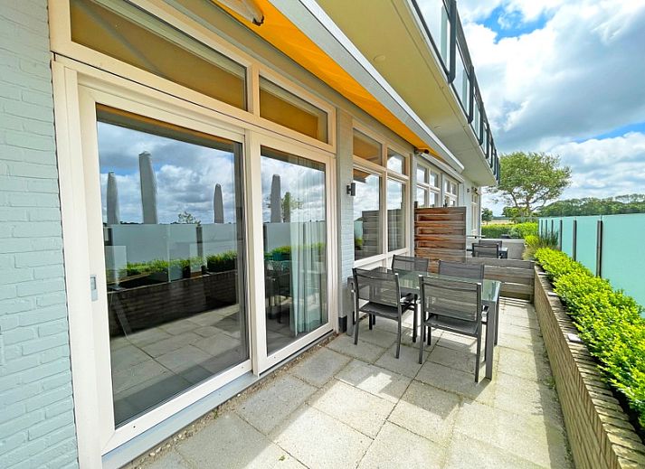 Gemuetliche Sitzecke im Apartment Bos en Duin 03, De Dennen, Texel mit bequemem Sessel und Blick auf die Terrasse.