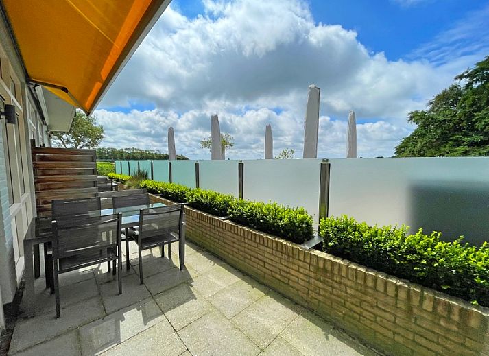 Gemuetliche Sitzecke im Apartment Bos en Duin 03, De Dennen, Texel mit bequemem Sessel und Blick auf die Terrasse.