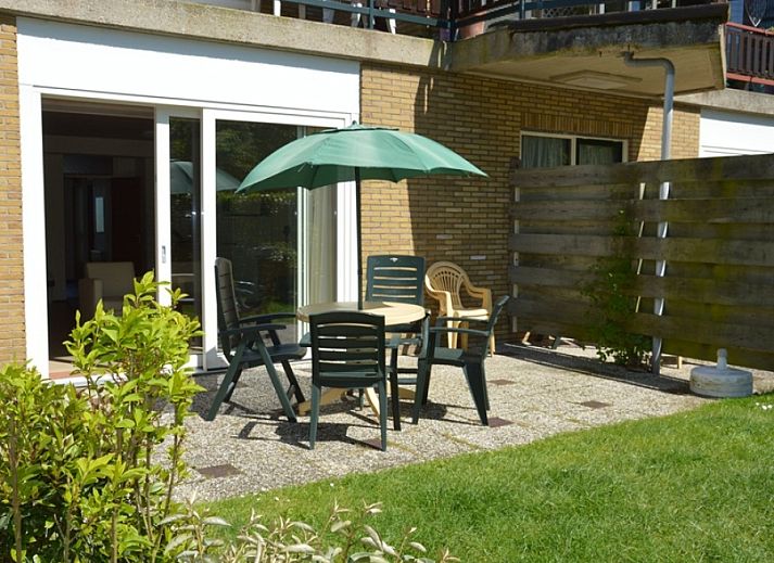 Terras bij vakantiehuis Anjer in De Dennen, Texel met tuinmeubilair en parasol.