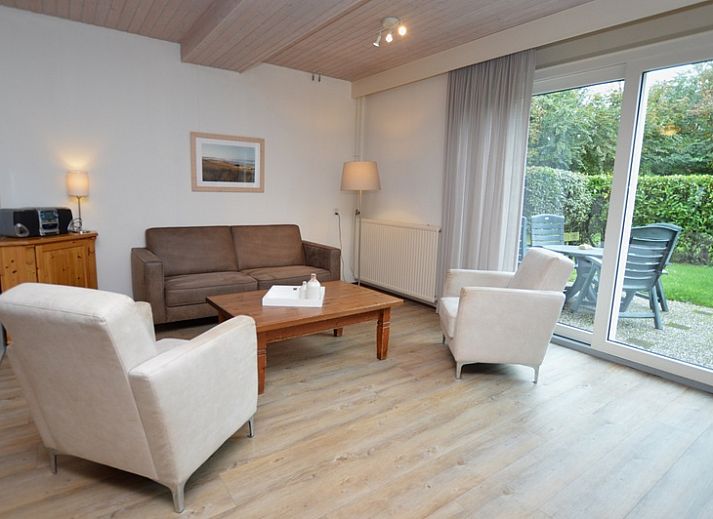 Terras bij vakantiehuis Anjer in De Dennen, Texel met tuinmeubilair en parasol.