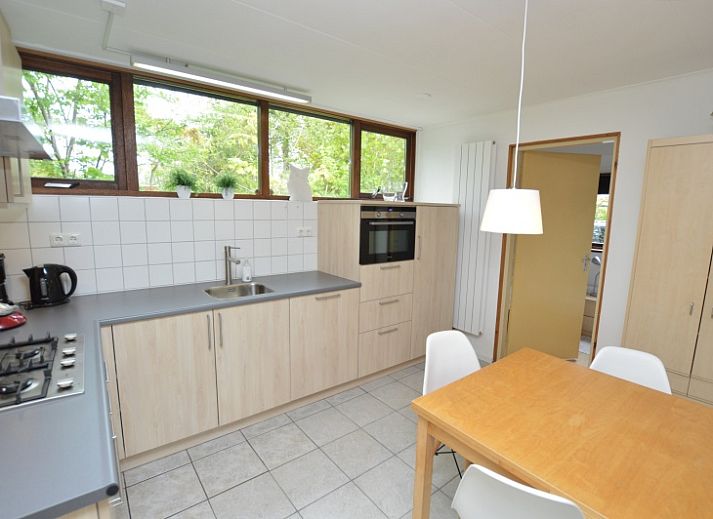 Gemuetliches Wohnzimmer des Ferienhauses de Parel 286 in De Dennen, Texel, mit farbenfroher Einrichtung und Gartenblick.