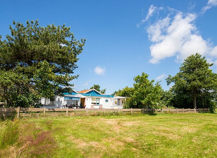 Meadow View vacation home in De Dennen, Texel overlooking green meadow and blue sky.