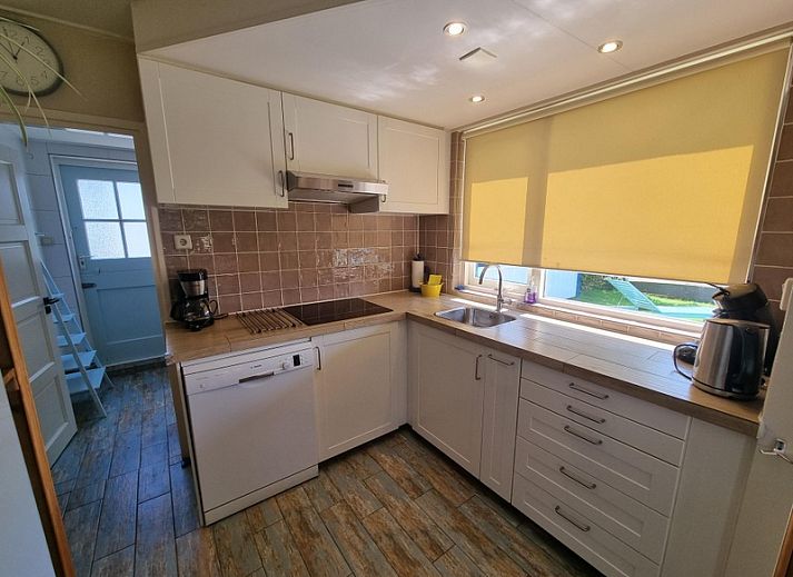Veranda of Weidezicht vacation home in De Dennen, Texel with deck chair and garden.