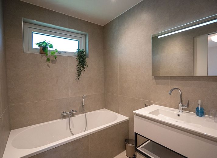 Gezellige woonkamer van Vakantiehuis de Parel 180 in De Dennen, Texel met uitzicht op de tuin.