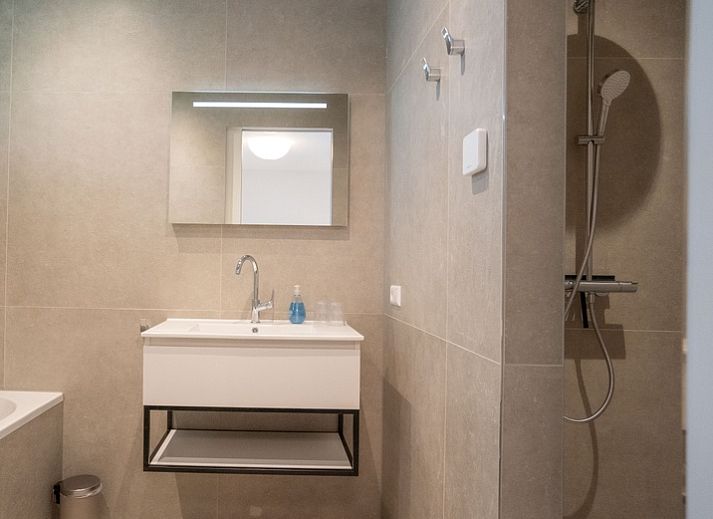 Lichte zithoek in Vakantiehuis de Parel 180, De Dennen, Texel met comfortabele banken en ramen naar de tuin.