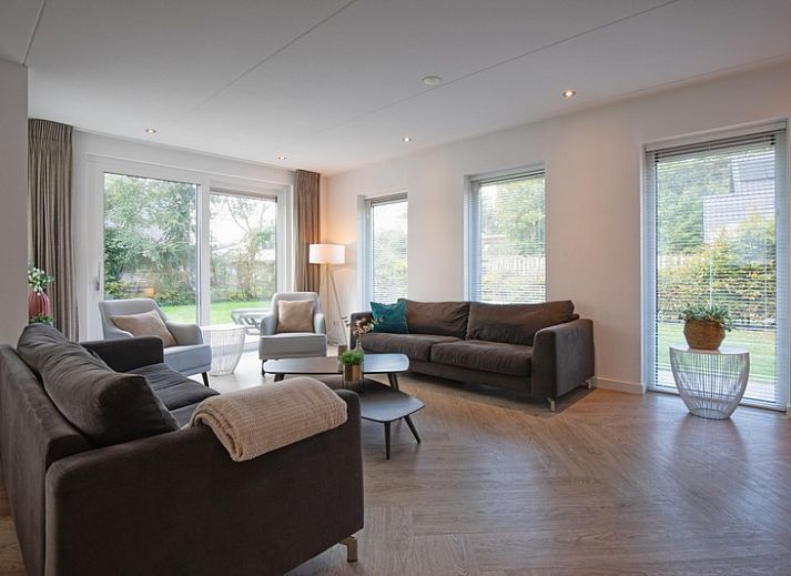 Gemuetliches Wohnzimmer in der Villa Bloem en Bos, Bungalowpark 't Hoogelandt, De Dennen, Texel, mit bequemen Sofas und Blick auf den Garten.