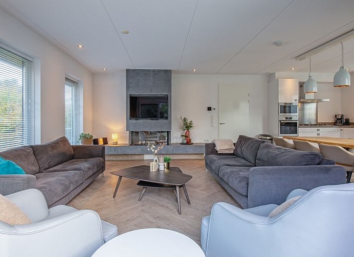 Gemuetliches Wohnzimmer in der Villa Bloem en Bos, Bungalowpark 't Hoogelandt, De Dennen, Texel, mit bequemen Sofas und Blick auf den Garten.