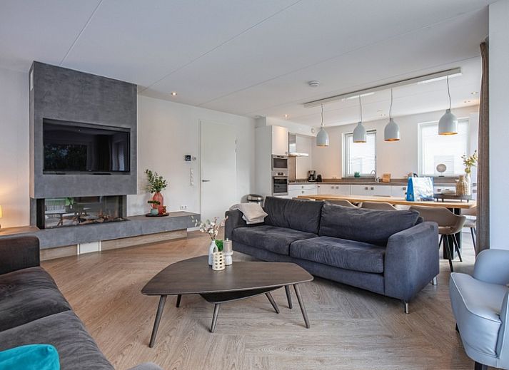 Gemuetliches Wohnzimmer in der Villa Bloem en Bos, Bungalowpark 't Hoogelandt, De Dennen, Texel, mit bequemen Sofas und Blick auf den Garten.