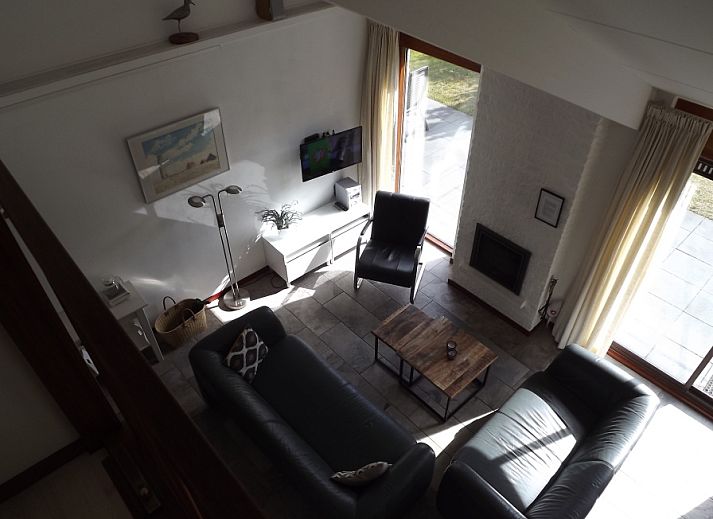 Gemuetliches Wohnzimmer im Ferienhaus Gortersmient 326, De Dennen, Texel mit bequemen Sitzgelegenheiten und Kamin.