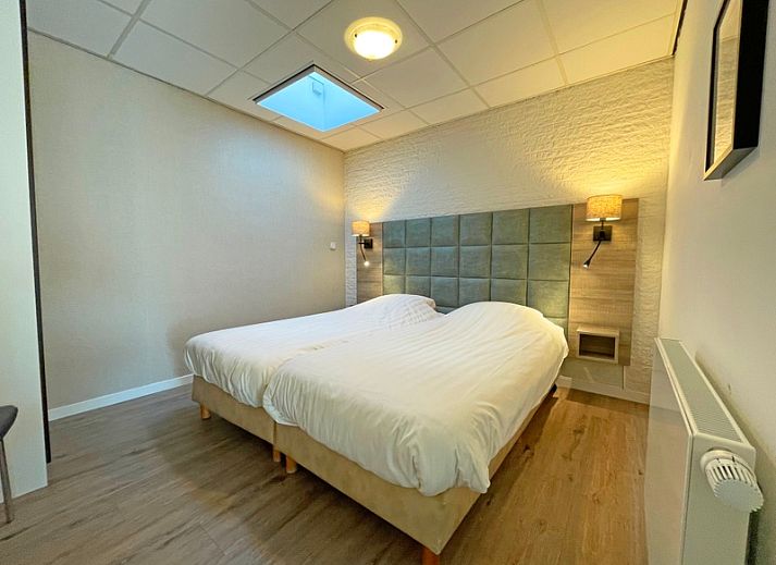 Helles Wohnzimmer des Appartements Bos en Duin 19, Texel mit gemuetlicher Sitzecke und grossen Fenstern.