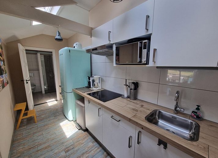 Sonnige Terrasse am Ferienhaus Boszicht in De Dennen Texel mit Liegestuehlen und Sonnenschirm.