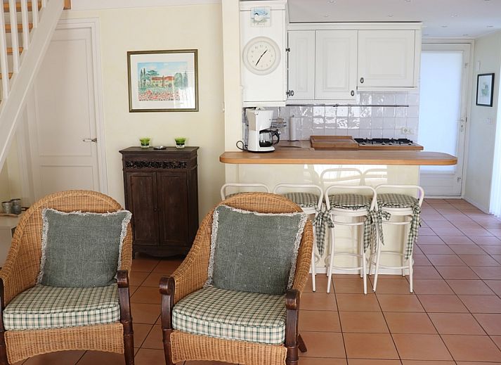 Gezellige binnenruimte in Vakantiehuis Gortersmient 264, De Dennen, Texel met rieten stoelen en keuken.