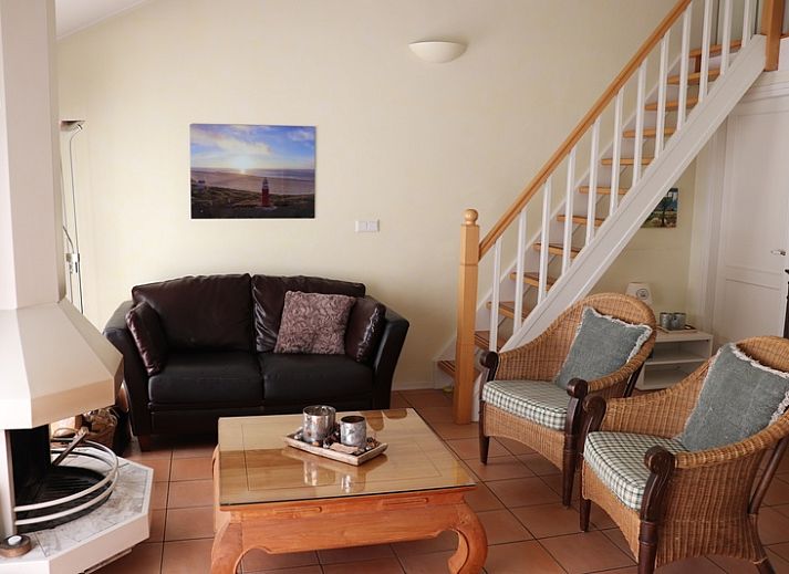 Gezellige binnenruimte in Vakantiehuis Gortersmient 264, De Dennen, Texel met rieten stoelen en keuken.