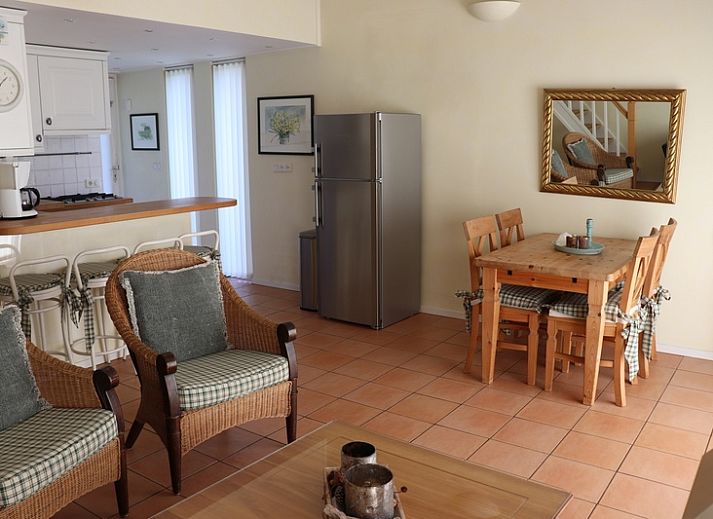 Gezellige binnenruimte in Vakantiehuis Gortersmient 264, De Dennen, Texel met rieten stoelen en keuken.