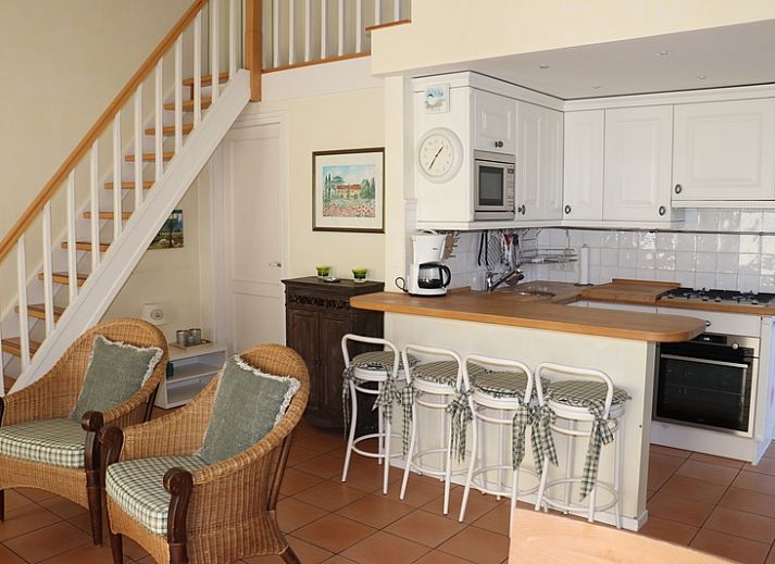 Gezellige binnenruimte in Vakantiehuis Gortersmient 264, De Dennen, Texel met rieten stoelen en keuken.