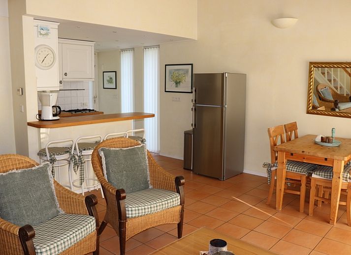 Gezellige binnenruimte in Vakantiehuis Gortersmient 264, De Dennen, Texel met rieten stoelen en keuken.