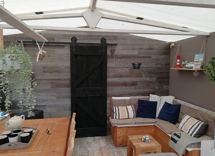 De Hagedis glamping lodge in Oost-Vlieland met terras en blauwe parasol tussen de duinen, Vlieland, Waddeneilanden.