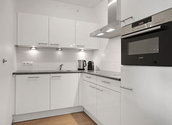 Gezellige woonkamer van het Vlieduyn 2-persoons appartement in Oost-Vlieland, met moderne meubels en flatscreen-tv.