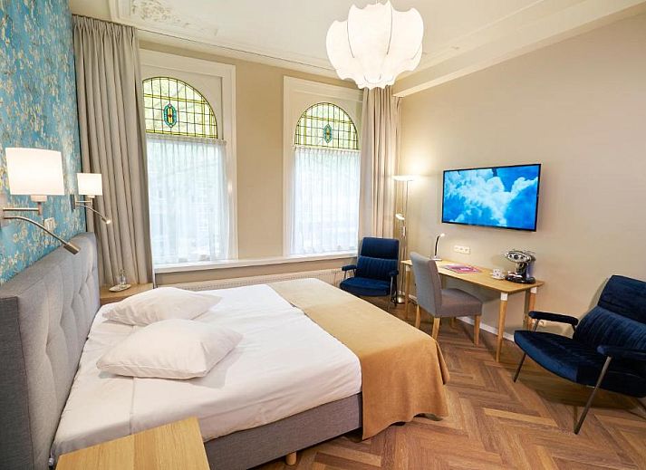 Buitenaanzicht van Hotel Van Walsum in Rotterdam, Zuid-Holland, met verlichte gevels en bomen in de avond.