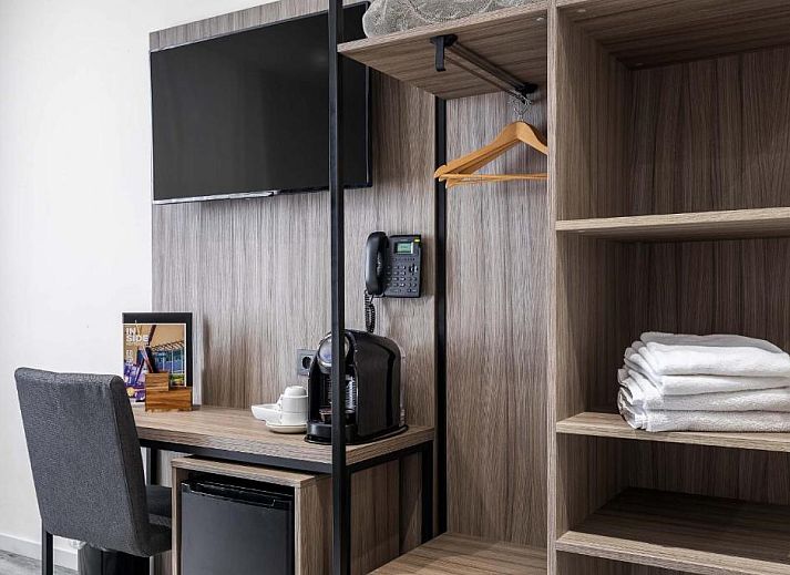 Praktische werkruimte in Hotel Milano, vakantieappartement in Rotterdam, met bureau, tv en opbergruimte.