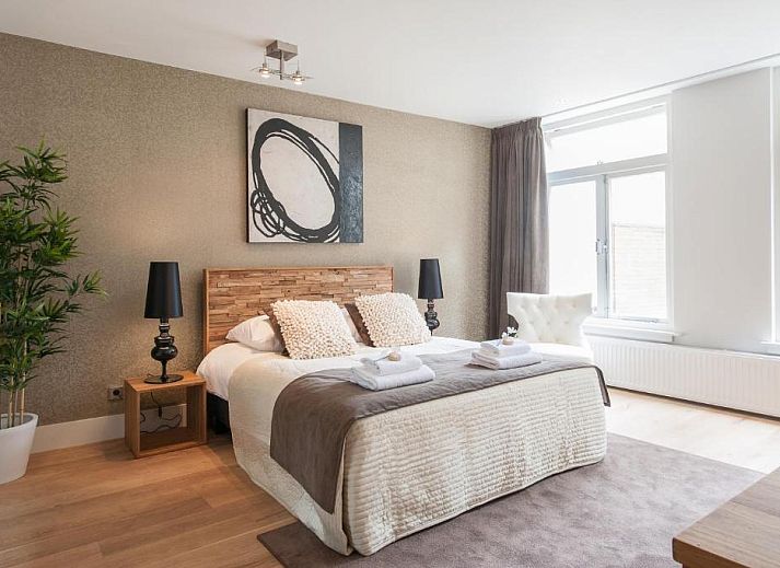 Comfortable bedroom in Museumpark Apartments, Rotterdam, with large window and wooden floor.